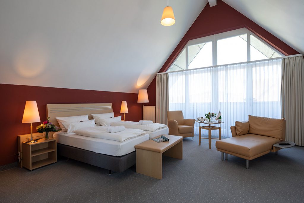 Gemütliches Doppelbett mit Sessel und Couch im Hotel Mainpromenade in Karlstadt