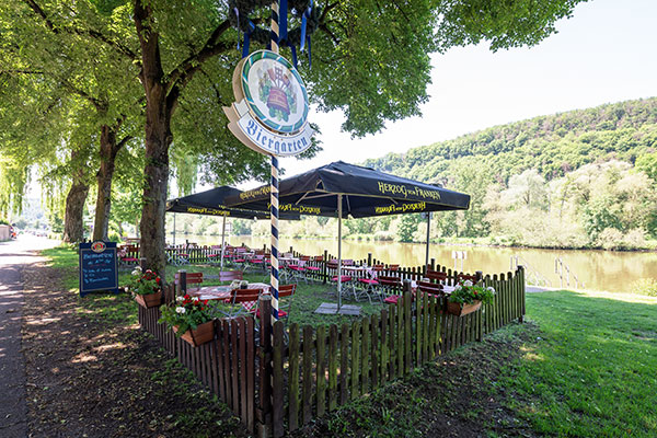 Biergarten des Restaurant Hotel Karlstadt direkt am Main unter Bäumen bei schönem Wetter