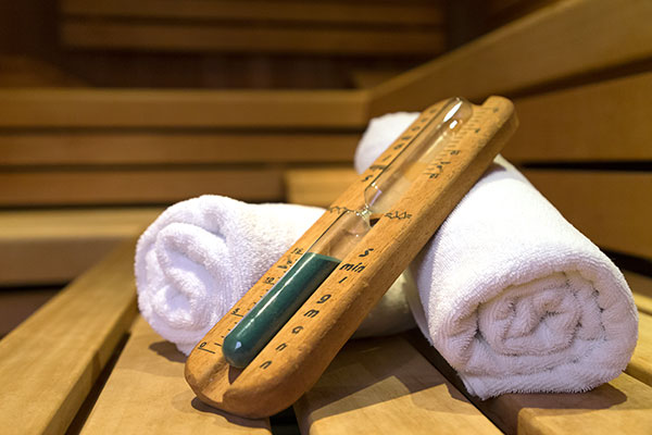 Eine Sanduhr liegt auf zwei aufgerollten Badetücher in der Sauna des Wellnesshotels in Mainfranken