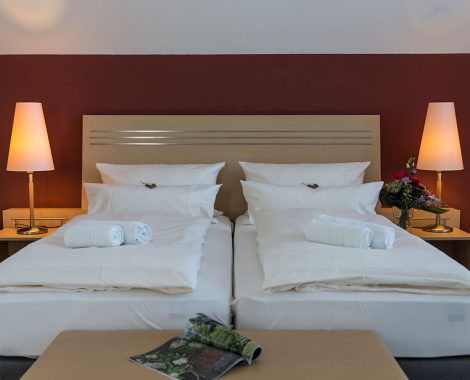 Modern eingerichtetes Doppelzimmer mit Nachttischlampen und gemütlichen Kissen im Hotel in Karlstadt